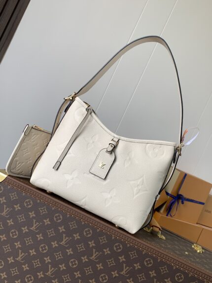 White handbag with brand logo and pattern, placed on top of other bags