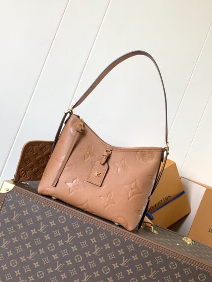 Pink leather handbag with brand logo, placed on top of other bags